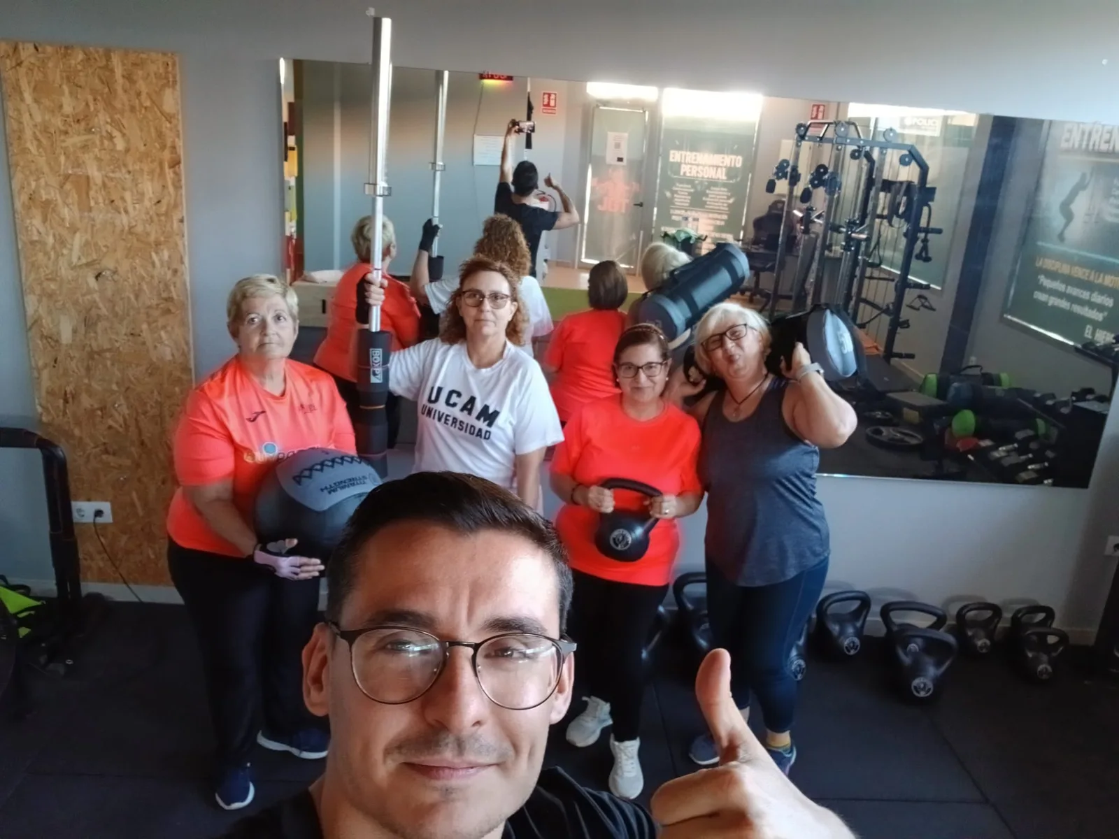 Jose Garcia con un grupo de personas entrenando en la sala, con kettlebells, balón medicinal y barra